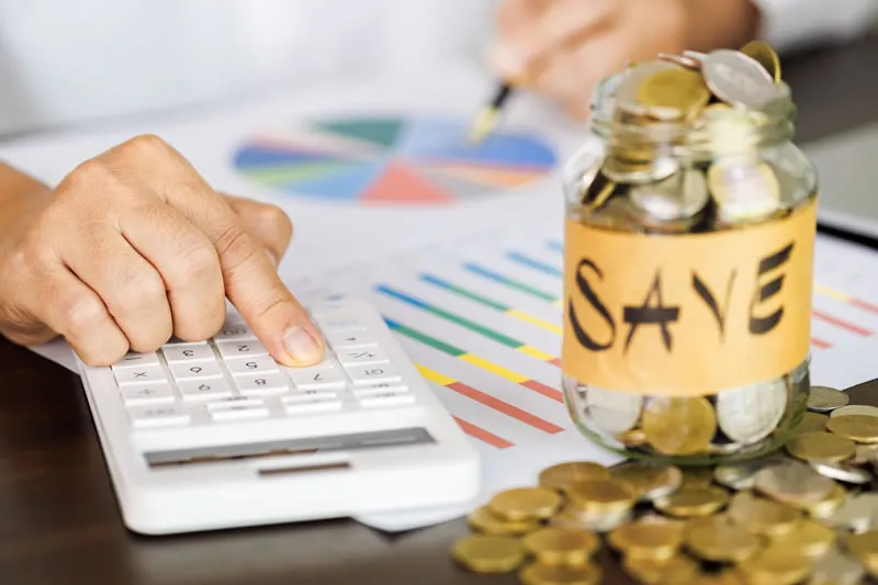 Calculadora e pote de moedas escrito SAVE representando economia sem juros