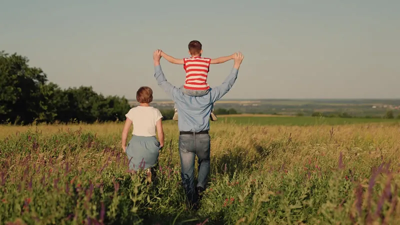 Familia de maos dadas caminhando no campo ao entardecer, realizando o sonho com planejamento