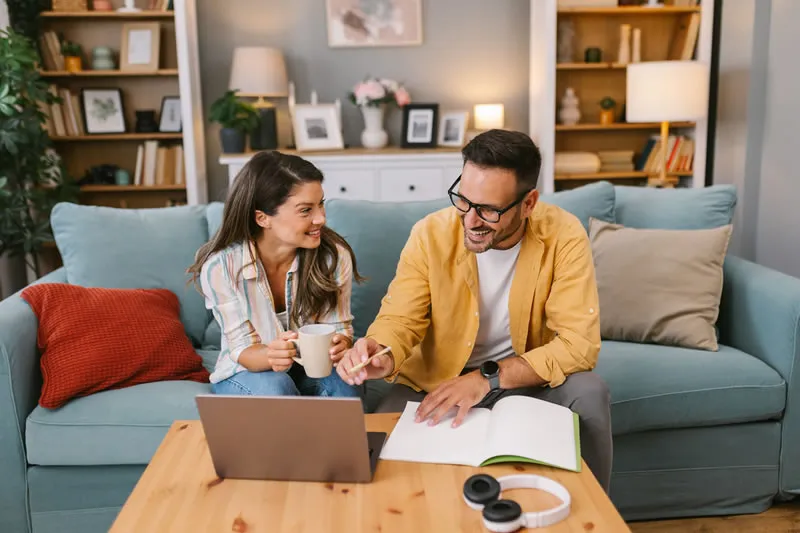 Casal organizando as finanças em casa com laptop e planejamento